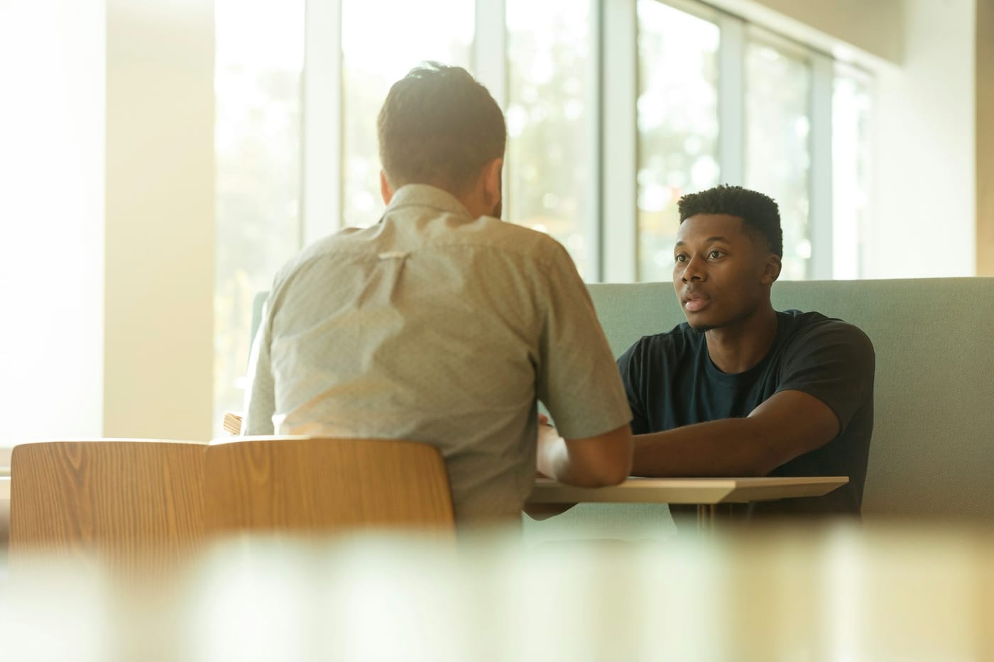 A manager and a member of his team in a one-on-one by a sunny window.